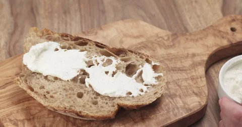 Spreading ricotta cheese on fresh rustic bread Stock Footage 77874768