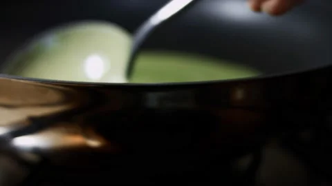 Spreading in round mooves green pancake batter in a pan for cooking pancakes Stock Footage 144904551