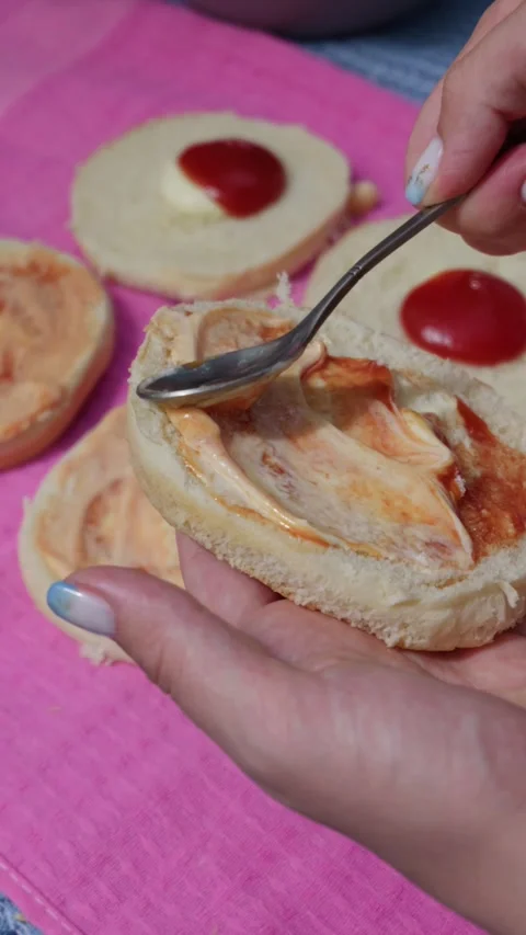Spreading Sauce on Fresh Hamburger Bun with Spoon for Homemade Burger Stock Footage 342000895