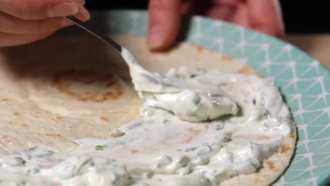 Spreading sauce made of yoghurt and fresh greens on a tortilla wrap. Stock Footage 154713006