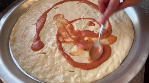 Spreading Sauce Over Dough on a Round Metal Tray for Baking Prep Stock Footage 344786353