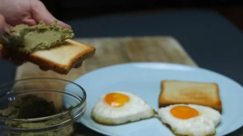 Spreading smashed avocado on toasts for breakfast. Cooking a surprise breakfast Stock Footage 150502295