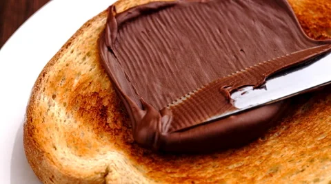 Spreading smooth and sweet hazelnut chocolate spread on freshly toasted bread Stock Footage 46880562