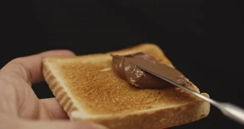 Spreading smooth and sweet hazelnut chocolate spread on freshly toasted bread Stock Footage 130740019