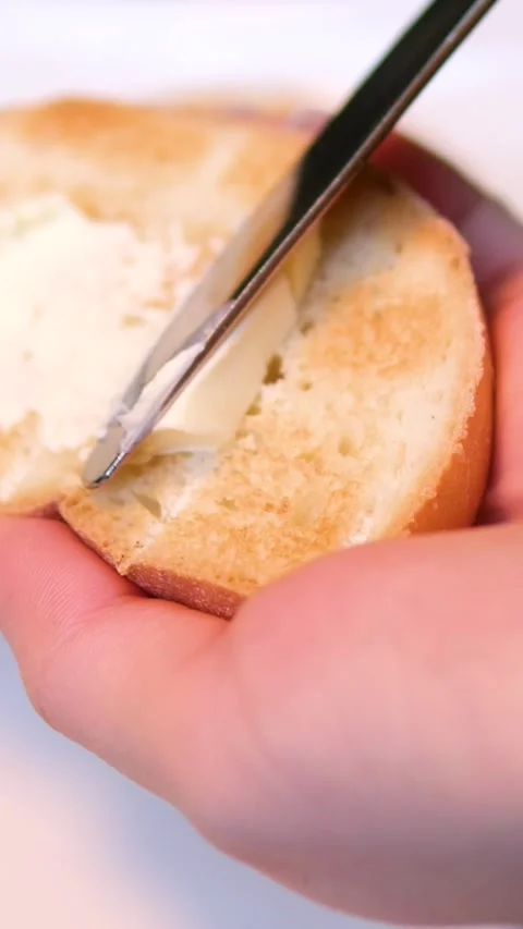 Spreading soft butter on a piece of toast bread. Making breakfast toast Stock Footage 323532256