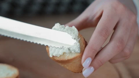 Spreading soft cheese on a slice of toasted bread, Close-up of a knife spreading Stock Footage 301557911
