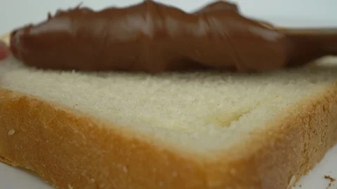 Spreading some Chocolate Cream on a Slice of Bread, Macro Stock Footage 98431163