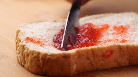 Spreading strawberry jam on bread. Video stock 128556549
