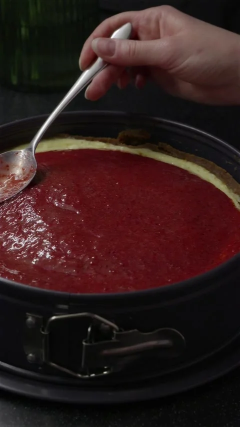 Spreading strawberry jam glaze on top of cheesecake close up Stock Footage 340610519