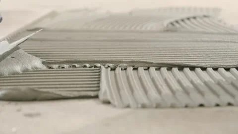 Spreading tile adhesive on the floor with a notched trowel. Construction work Stock Footage 340010102