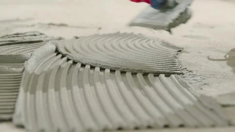 Spreading tile adhesive on the floor with a notched trowel. Home renovation. Stock Footage 340934604