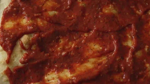 Spreading Tomato Marinara Sauce on Raw Pizza Dough with Spoon. Stock Footage 319033083