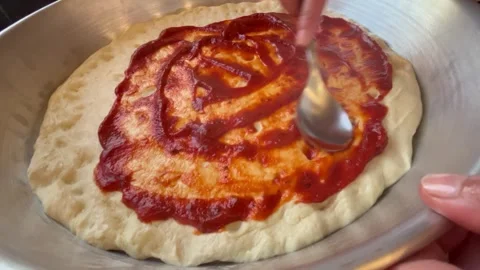 Spreading Tomato Paste Sauce Over Flatbread Dough on a Metal Tray Stock Footage 344786437