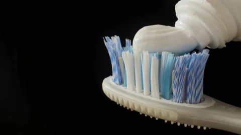 Spreading toothpaste on the toothbrush. The macro plan. Black key. Black backgro Stock Footage 144907282