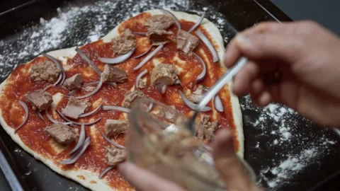 Spreading tuna chunks over pizza dough. Preparing heart shaped tuna pizza for Stock Footage 146926510