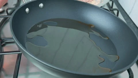 Spreading/shaking a pan in order to cover the bottom surface with oil in 4K. Stock Footage 141305139