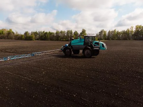 Spring agricultural work in the fields. The tractor sprays crops with herbicides Stock Photos