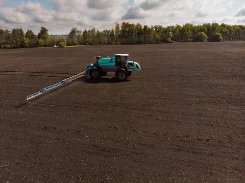 Spring agricultural work in the fields. The tractor sprays crops with herbicides Stock Photos