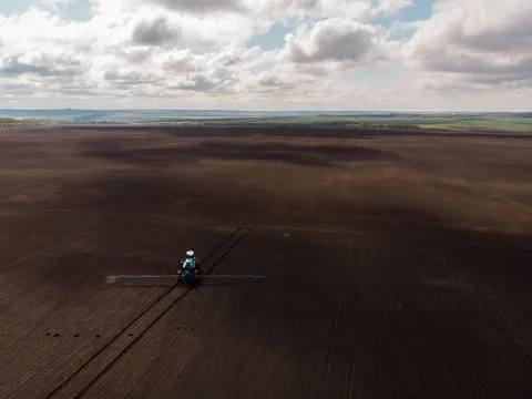 Spring agricultural work in the fields. The tractor sprays crops with herbicides Stock Photos