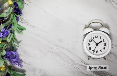 Spring ahead white clock and lilac sage flowers on gray marble (1) Stock Photos