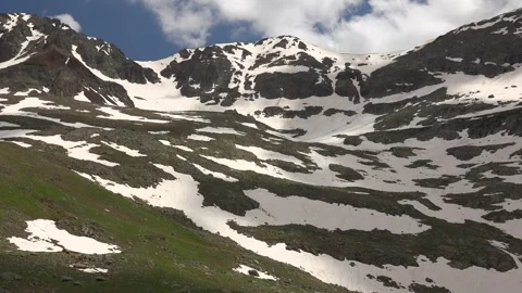 Spring alpine meadow with melting snow on mountain slopes - Peaks and Snowmelt Stock Footage 339507206