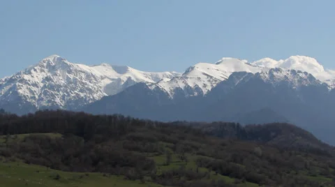 Spring and winter together, snowed mountains and green field Stock Footage 25600966