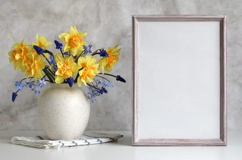 Spring background, mockup. an empty wooden frame and a garden bouquet of daff Foto stock