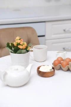 Spring breakfast concept. White pot with flower, eggs, teapot, glass of tea and Stock Photos