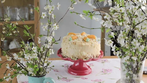 Spring cake decorated with pastel eggs and flowers, placed on a red stand. A Stock Footage 303516360