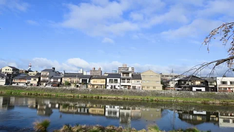 Spring Cherry Trees and Riverside Houses Reflected in Kyoto River Stockbeeldmateriaal 348750186