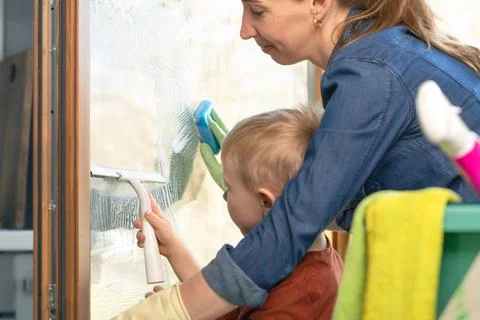 Spring cleaning of a window with a squeegee on a sunny warm day. Clean and .. Stock Photos