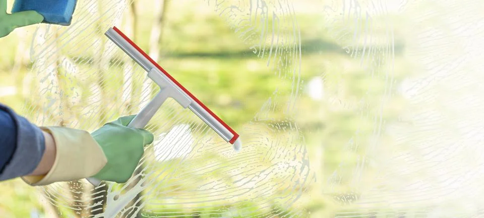 Spring cleaning of a window with a squeegee on a sunny warm day. Clean and .. Stock Photos