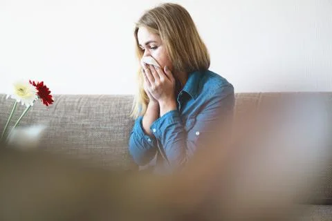 Spring cold or allergies. Attractive girl is allergic to flowers, uses a napkin Stock Photos