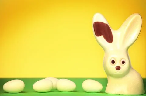 A spring composition of a white chocolate easter bunny and eggs over yellow.. Stock Photos