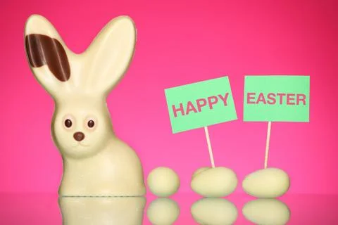 A spring composition of a white chocolate easter bunny and eggs over pink b.. Stock Photos