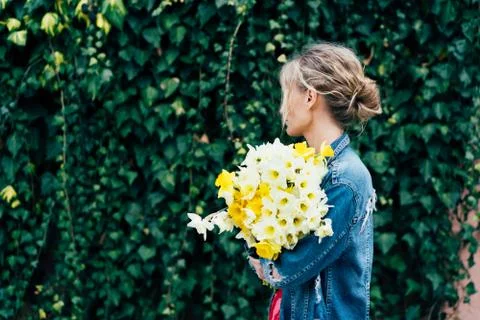 Spring content. Young charming blonde hipster with a bouquet of daffodils Foto stock