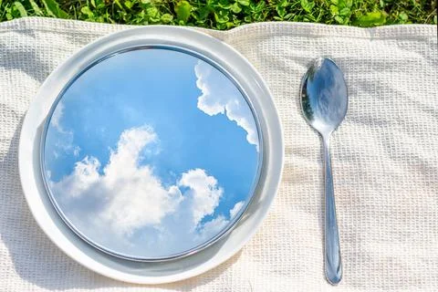 A spring creative photo, a reflection of the blue sky with clouds in a plate Stock Photos