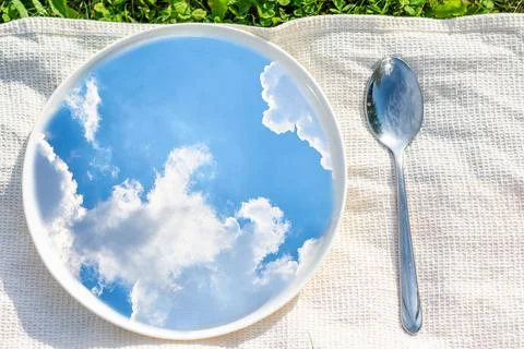 A spring creative photo, a reflection of the blue sky with clouds in a plate Stock Photos