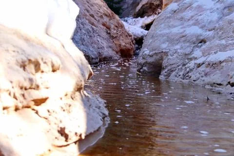Spring creek between two steep sandy banks with snow Stock Photos