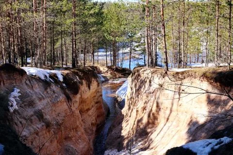 Spring creek between two steep sandy banks with snow Stock Photos