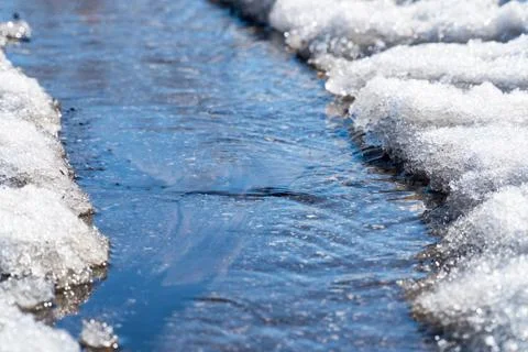 Spring creek flows through the asphalt Stock Photos