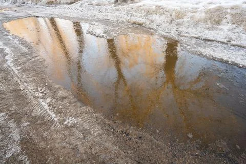 Spring day, big puddle on the sidewalk. Snow is melting Stock Photos