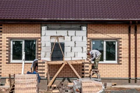 Spring day, workers make the finish facade of the house Stock Photos