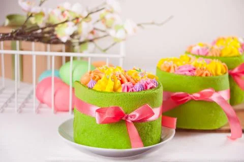 Spring Easter festive table. Small green cakes with butter cream flowers and  库存照片