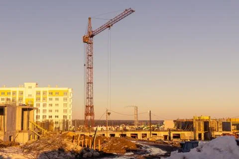 On a spring evening, a tower crane builds buildings on the outskirts of the city Stock Photos