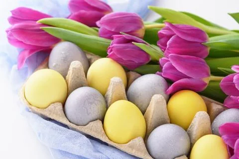 Spring festive Easter composition of paschal eggs and purple tulips on white Stock Photos
