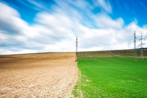 Spring field with electric pillars Stock Photos