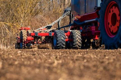 Spring field prep with red seed drill and tractor in farmland Stock Photos