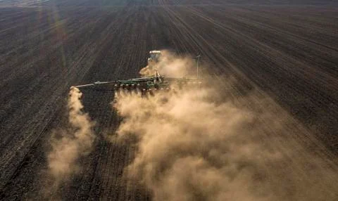 Spring field work, a tractor with a mounted seeder sow seeds in the ground Stock Photos