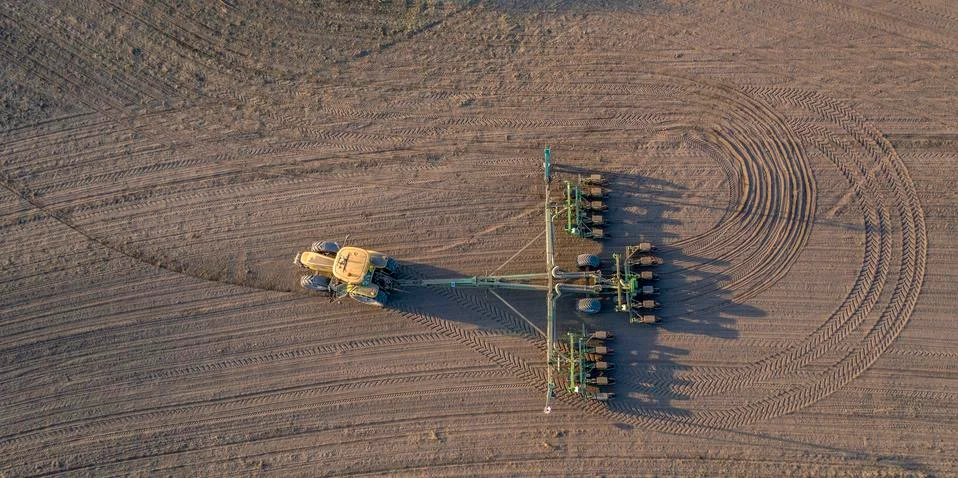 Spring field work, a tractor with a mounted seeder sow seeds in the ground Stock Photos
